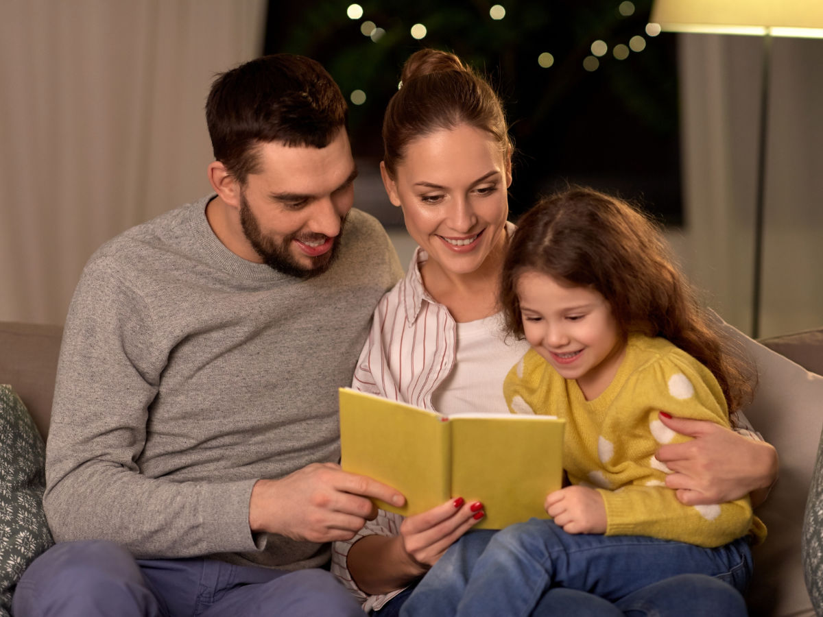 Foster parents and a child reading a book together